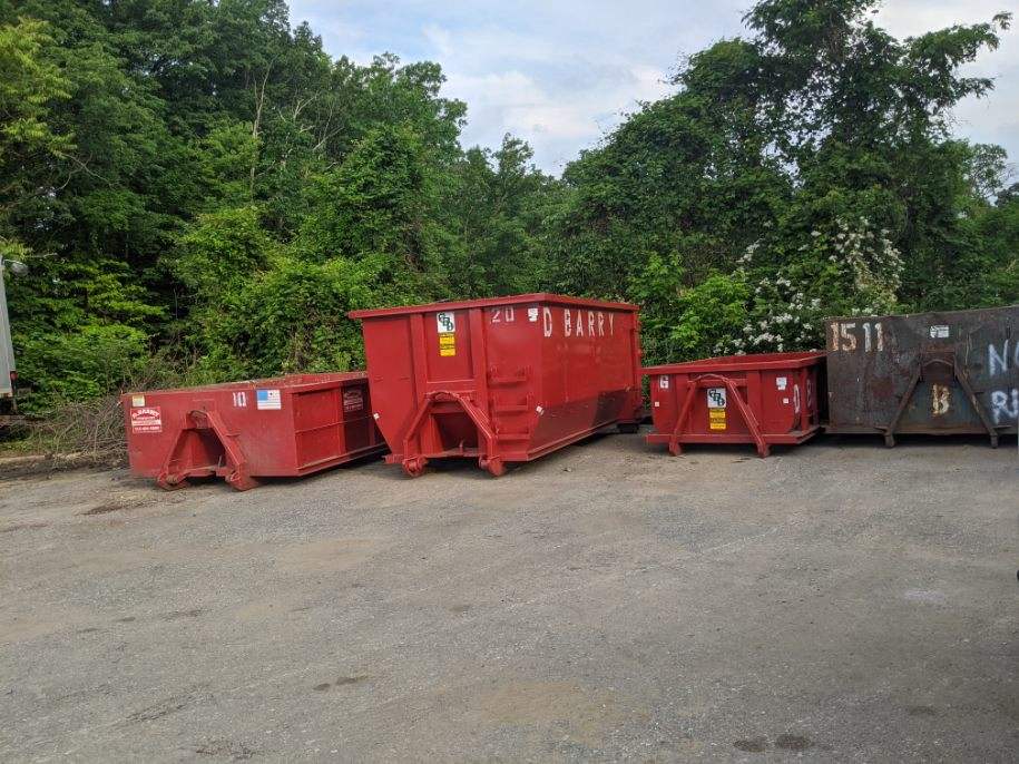 Rental dumpsters from D. Barry Rubbish Inc. lined up in an empty lot