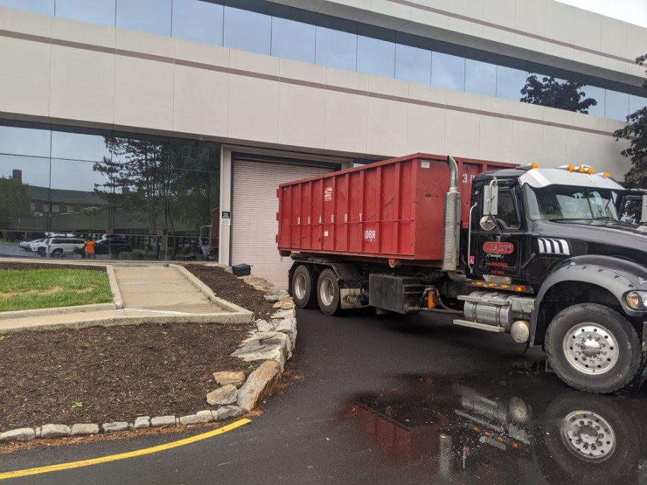 Dumpster rental truck outside of office building on a rainy day