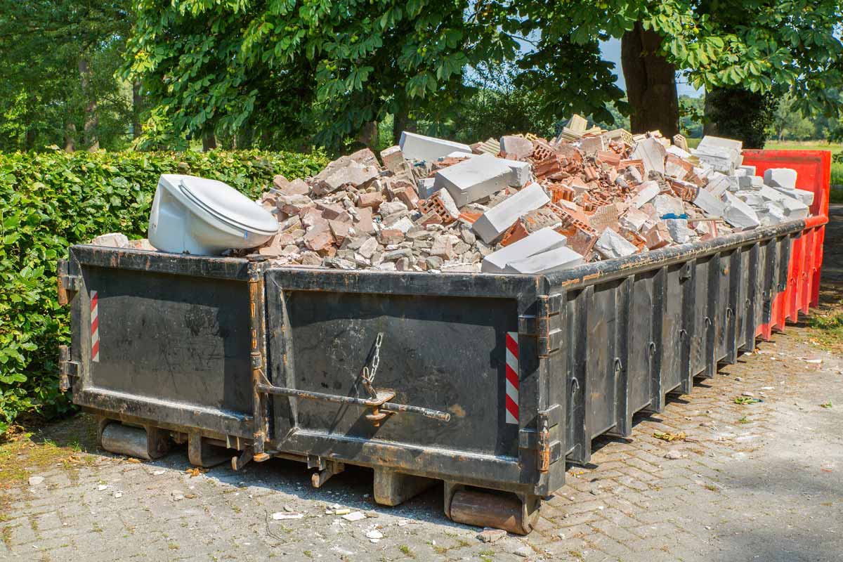 Dumpster full of bricks, cinderblocks, and an old toilet